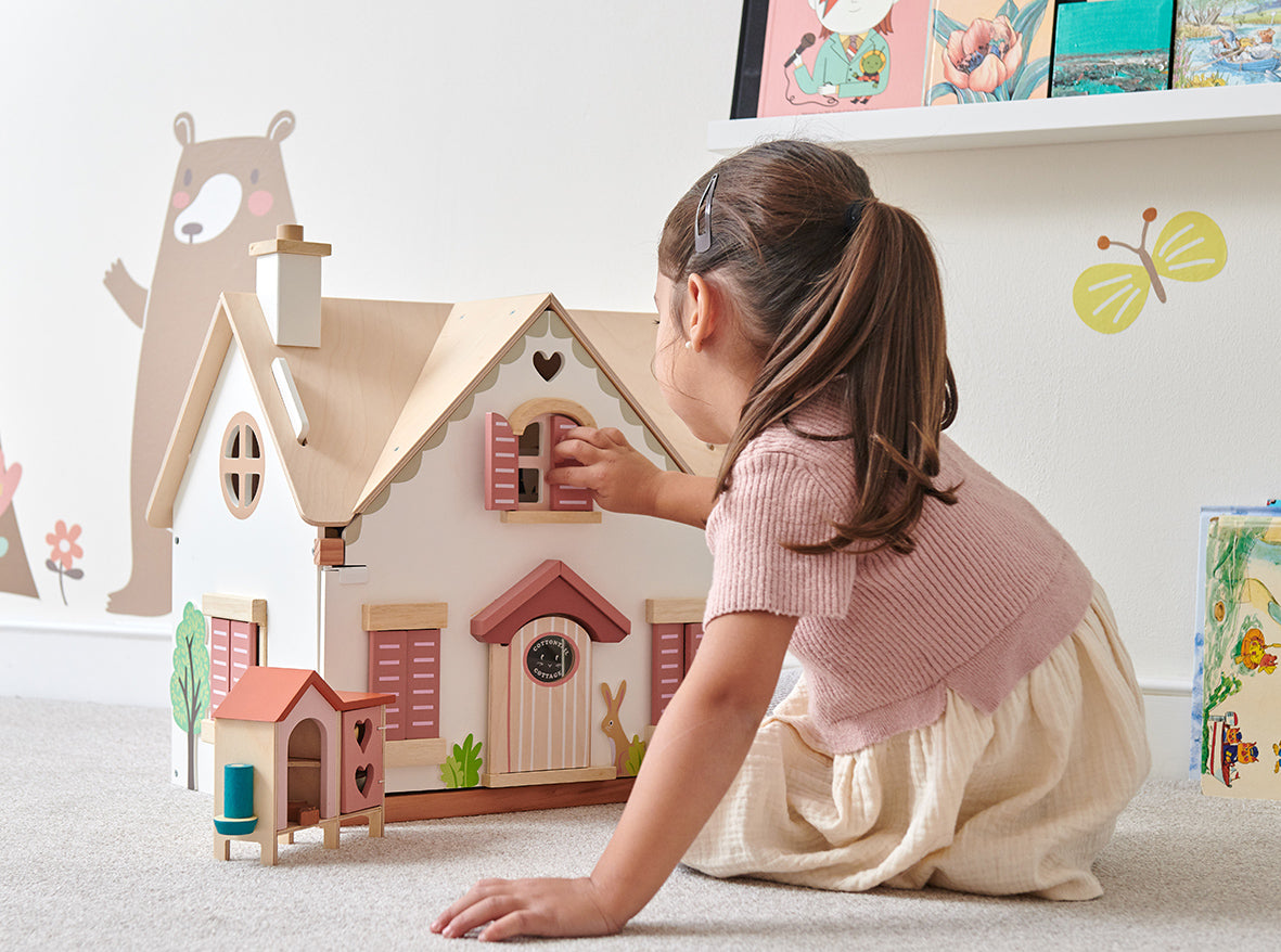 Girl playing with Tenderleaf Toys Cottontail Cottage dolls house