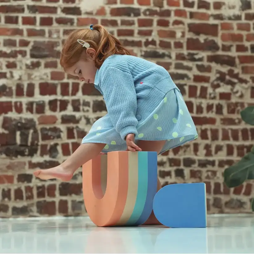 A girl sitting on the Moes rainbow set