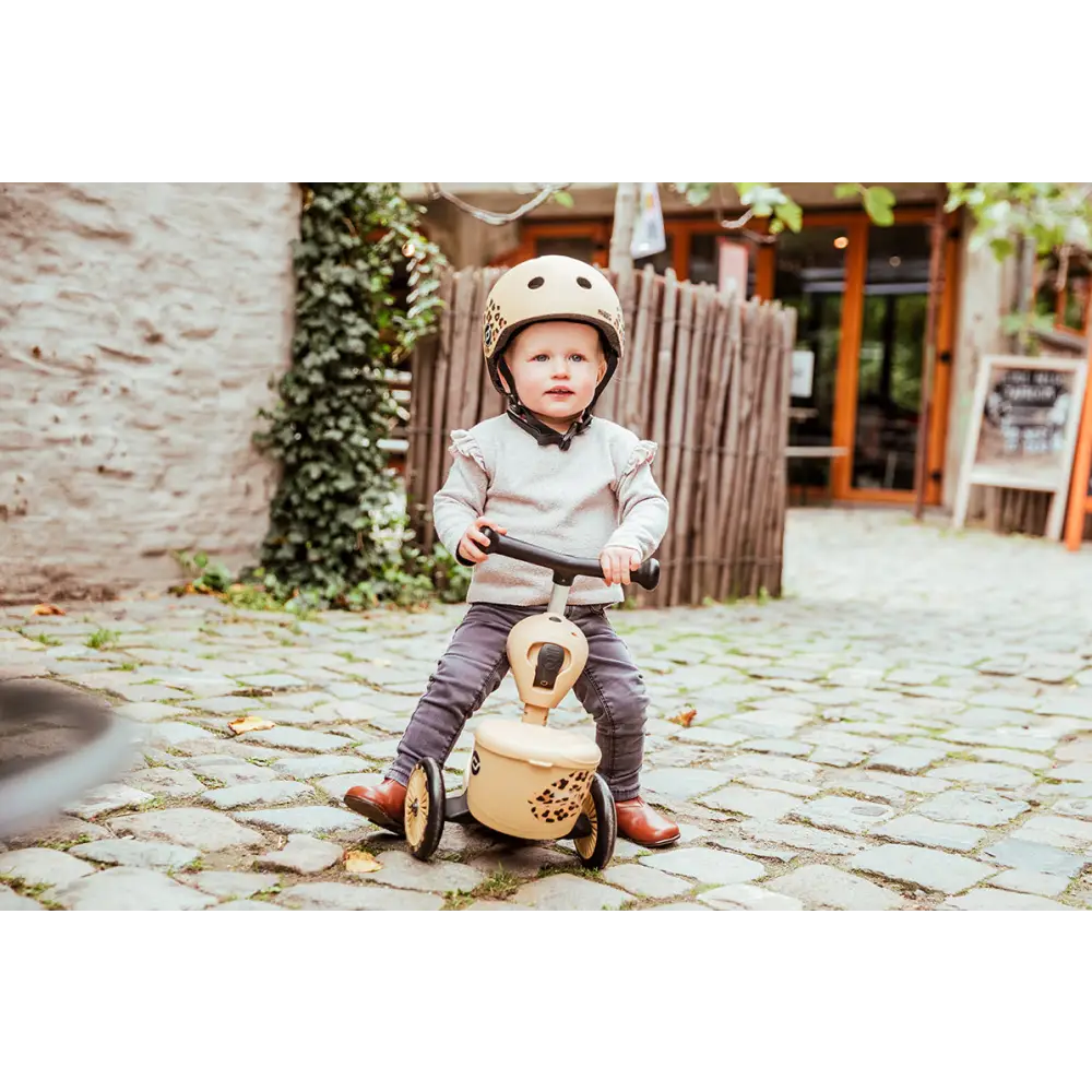 A girl sitting on the Scoot & Ride Highway Kick 1 Lifestyle Leopard Scooter