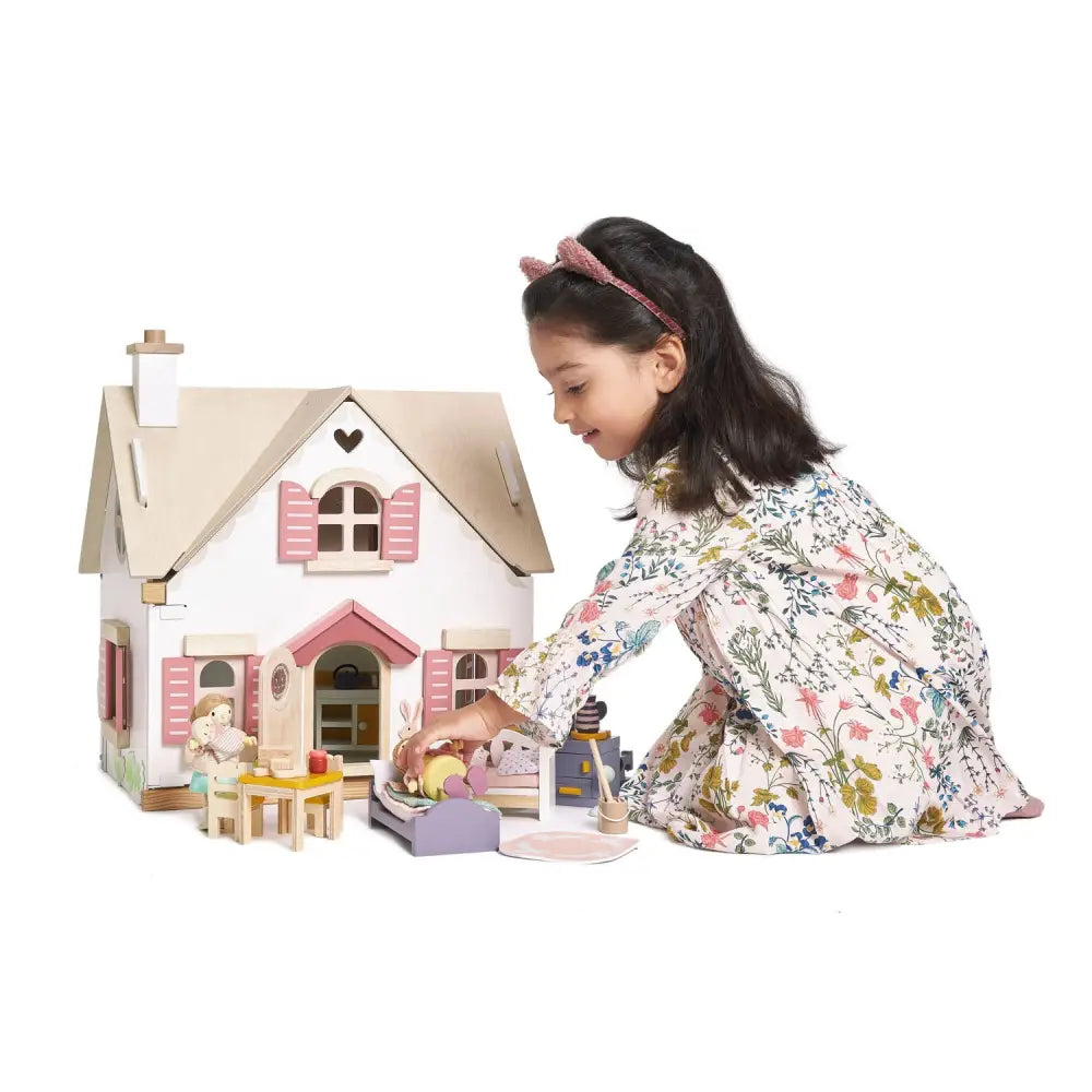 A girl playing with the Tenderleaf Toys Cottontail Cottage dolls house