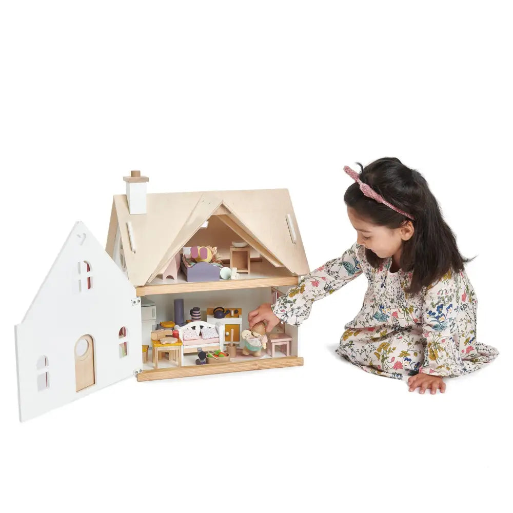 A girl playing inside the Tenderleaf Toys Cottontail Cottage dolls house