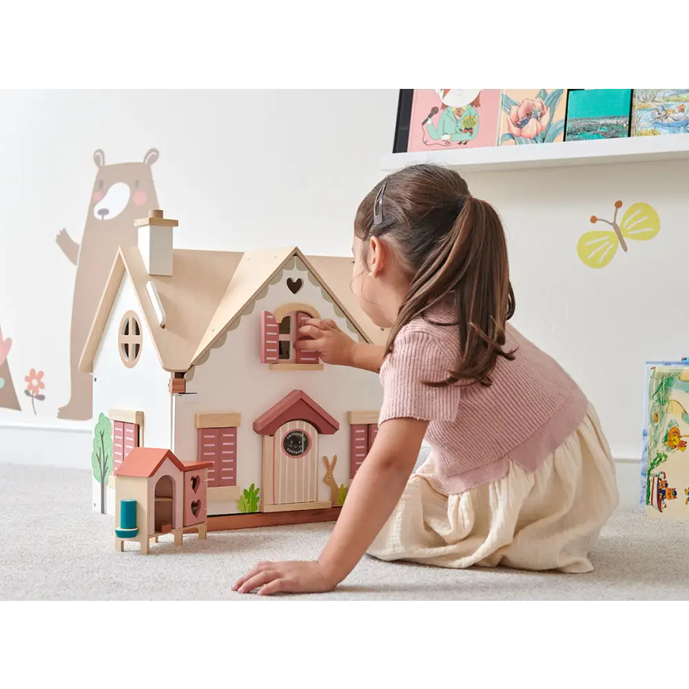 Girl playing with Tenderleaf Toys Cottontail Cottage dolls house